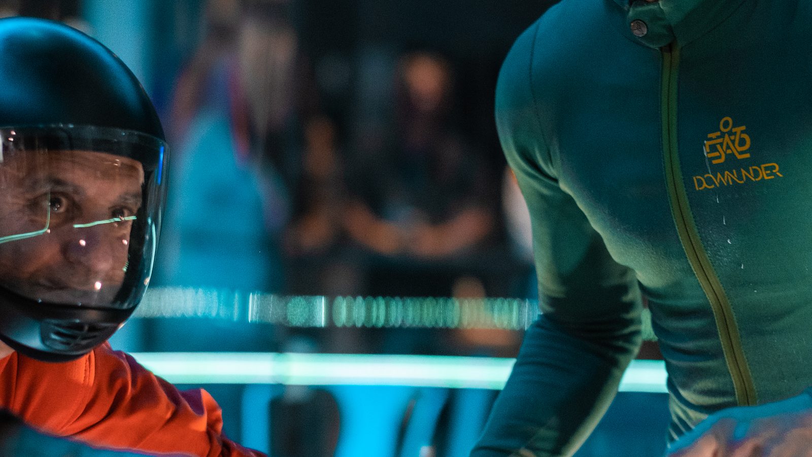 Mason coaching a flyer in the wind tunnel, guiding their arm mid-flight