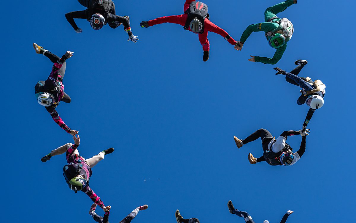 Skydivers flying formation together above farmland