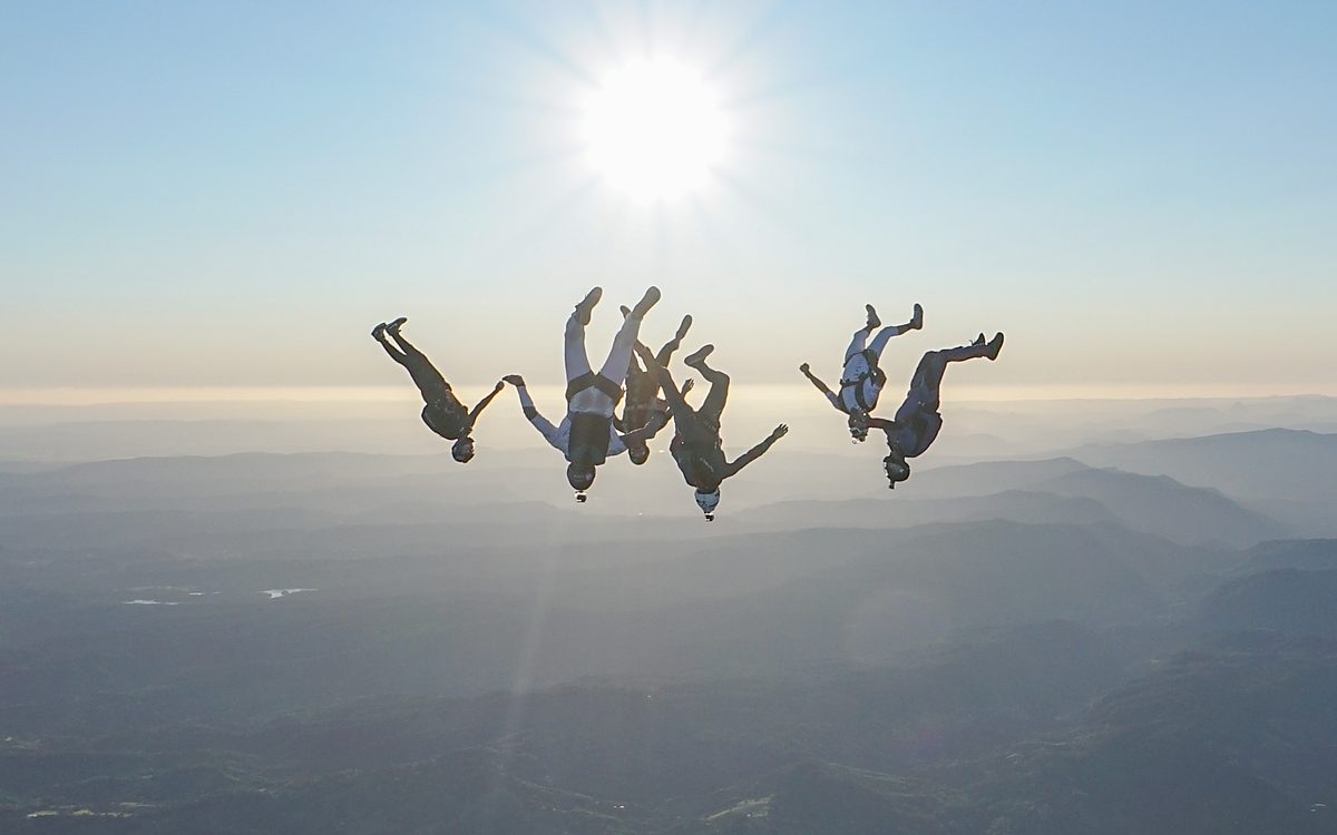 A lone skydiver in freefall silhouetted against the sun