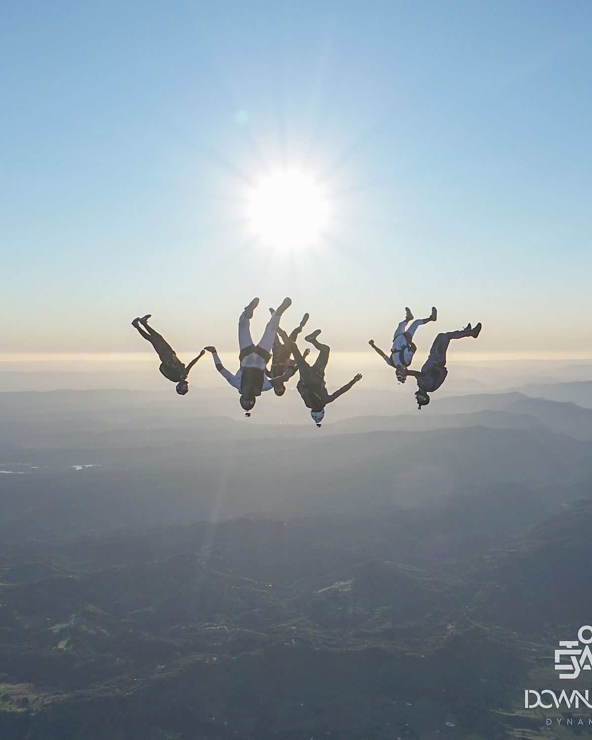 A lone skydiver in freefall silhouetted against the sun